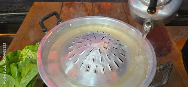 Obraz Pour the hot broth from the vintage kettle into the Pan roasted pork for the Thai barbecue Grill Pork. Barbecue buffet pig pan and vegetables in soup. Meat is often placed above the broth to cook.
