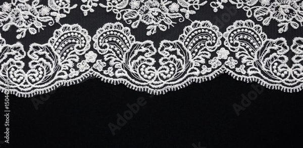 Fototapeta White lace close-up on black background. Texture banner. Selective focus and copy space