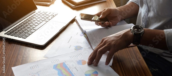 Fototapeta Businessman hand checking and planning financial data on smartphone.Professional Accountant checklist, annual report, summary report, and paper on office desk. Business man and planner concept.