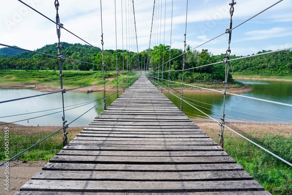 Obraz Wooden footbridge in nature tropical forest for trail route. Walking swing bridge, a suspension bridge across jungle, path way at Kaeng Krachan National Park, Phetchaburi Province,Thailand.