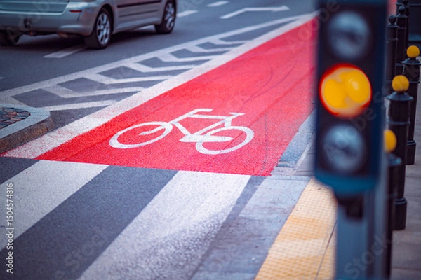 Obraz Brightly painted bicycle lane at a busy intersection features a traffic signal changing colors. Late afternoon light enhances the scene