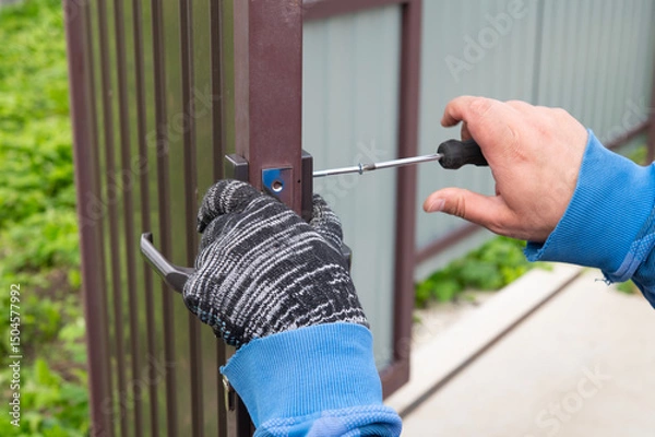 Fototapeta Installing a door lock. The worker selects a bolt for the door lock.
