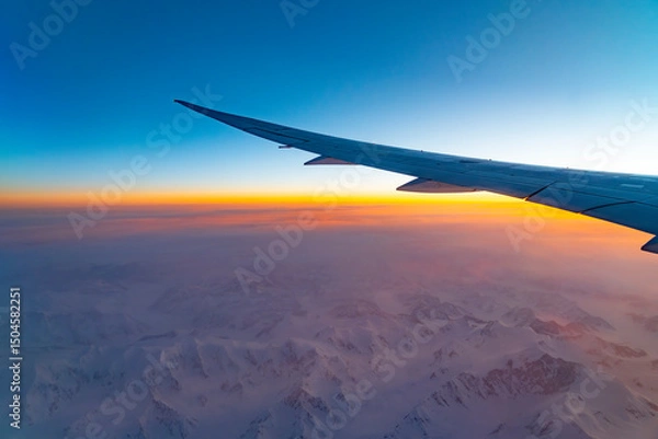 Fototapeta airplane wing above snow mountain in sunrise light