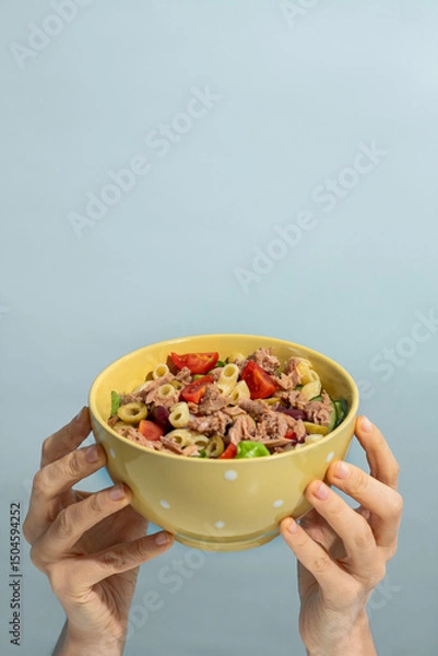 Obraz Woman holding bowl of delicious salad with canned tuna at blue background, top and front view. Space for text