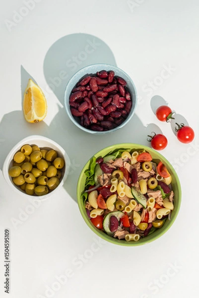 Obraz Healthy Green salad with tuna, cherry tomato, macaroni, bean, and olives on white table background. Balanced diet