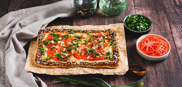 Fototapeta Appetizing galette with tomatoes, cheese and herbs on the table web banner