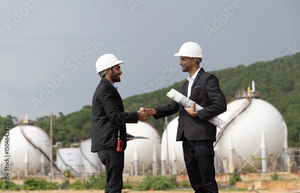Obraz Two Business Man or Investor with black suit and safety hat working with drawing and digital tablet due business at front Refinery and gas petrochemical plant  
