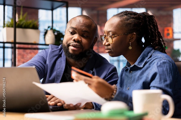 Fototapeta Responsible couple paying bills and doing their taxes on the laptop, entering payment details on web and confirming the money transfer. Online banking and managing finances at home.