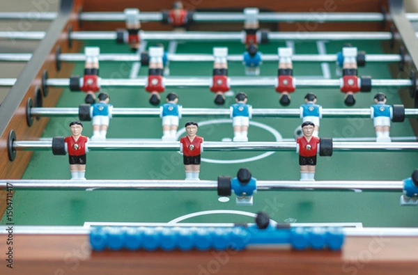 Fototapeta Close-up view of a foosball table with red and blue teams ready to play. Fun and competitive tabletop soccer game, perfect for recreation and entertainment.
