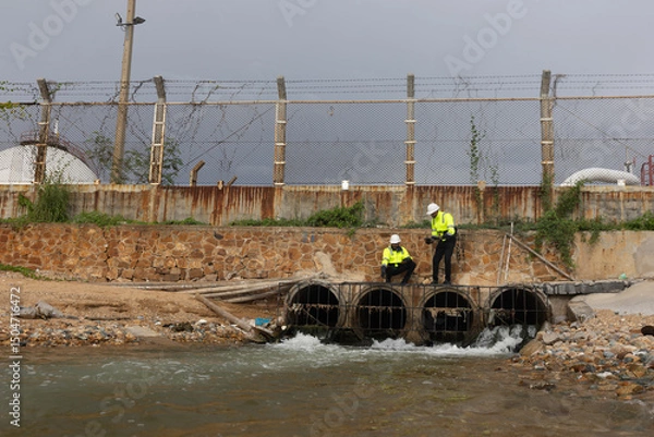 Fototapeta Environment engineer team with green safety jacket and PPE audit environment and quality of wastewater drain from factory 
