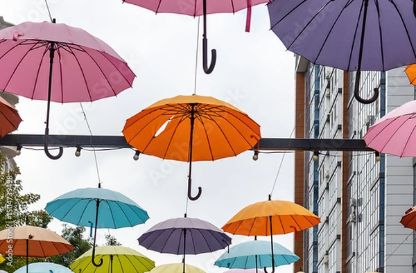 Obraz among the colorful umbrellas floating in the air, an orange umbrella broke off