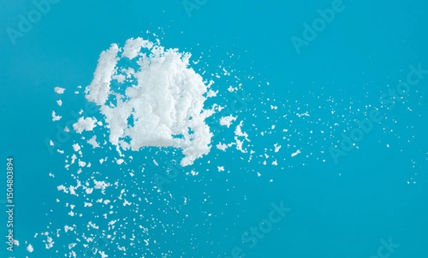 Fototapeta Snow dust element falling over blue sky. Fluffy White snow splash flying or throwing in mid air. Snowfall on blue background isolated