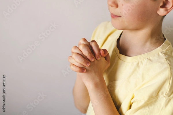 Obraz A boy with folded hands in front of him, he is praying or meditating. Concept of Christianity, religion and faith.