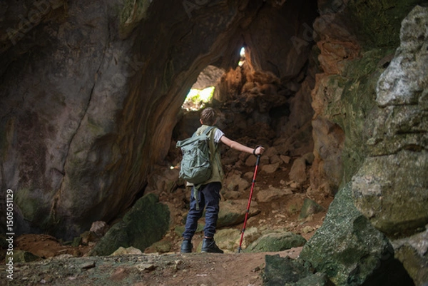 Fototapeta Tourist trekking with backpack and using a walking stick, gesturing forward suggesting of adventure or discovery in cave mysterious and ancient outdoor adventure concept.
