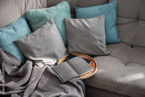 Fototapeta Open Book on Round Tray Rests on a Gray Sofa Draped with Soft Blanket. A Cozy Living Room Scene.