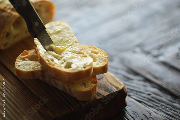 Obraz Spreading Butter on Freshly Sliced Rustic Bread on Wooden Cutting Board