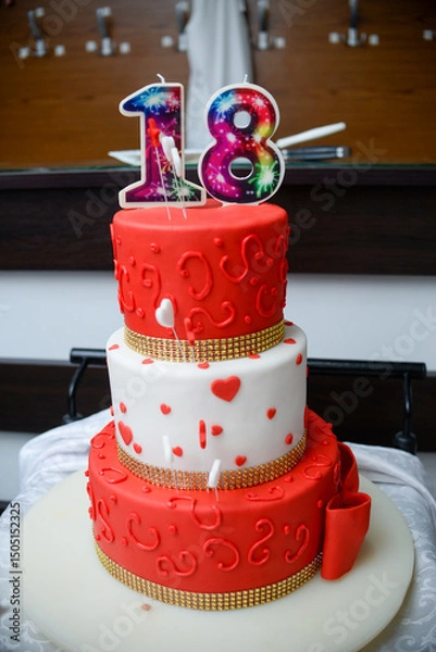 Fototapeta September 24, 2022 - Belgrade, Serbia. Red and white birthday cake with the emblem of the Red Star football club and the female name Nancy as well as a candle on top of the shape of the number eightee
