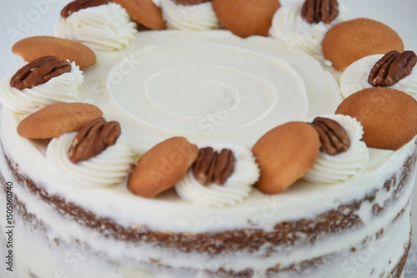 Fototapeta Delicious Carrot Cake with Nut Decorations spiced cake layers covered in smooth cream cheese frosting closeup side view of classic and delicious cake