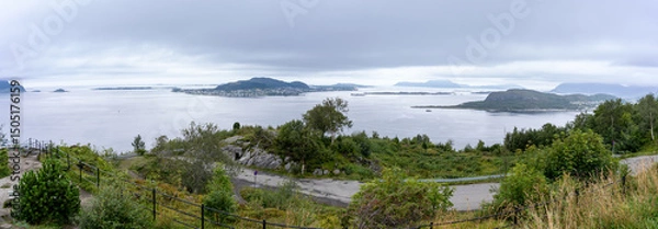 Fototapeta Panoramic view of the islands surrounding Alesund on Norway’s west coast, seen from Mount Aksla on a cloudy day, with lush greenery and calm coastal waters