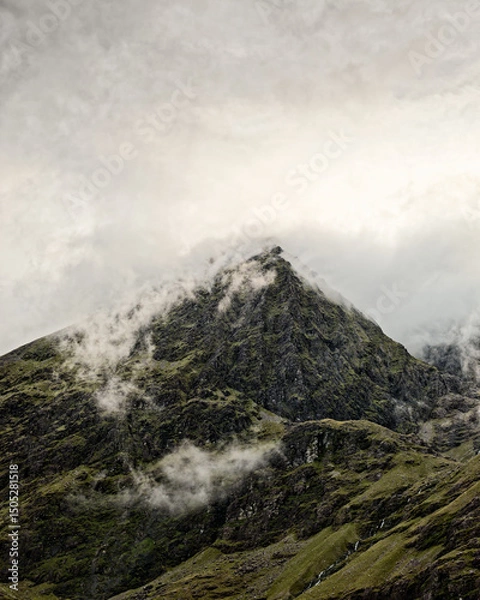 Fototapeta Carrauntoohil, the highest peak in Ireland, looks really impressive in the lush landscape. There are clouds swirling around the top of the mountain, which makes it look really dramatic and grand.