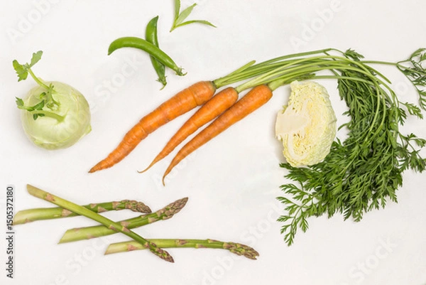 Fototapeta Spring carrots with green tops, green peas and savoy cabbage. Kohlrabi and lime on table