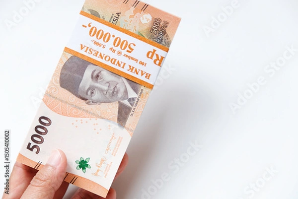 Obraz Hand holding Indonesian rupiah Rp 5.000 banknotes isolated on white background for THR on Eid al-Fitr or Lebaran days