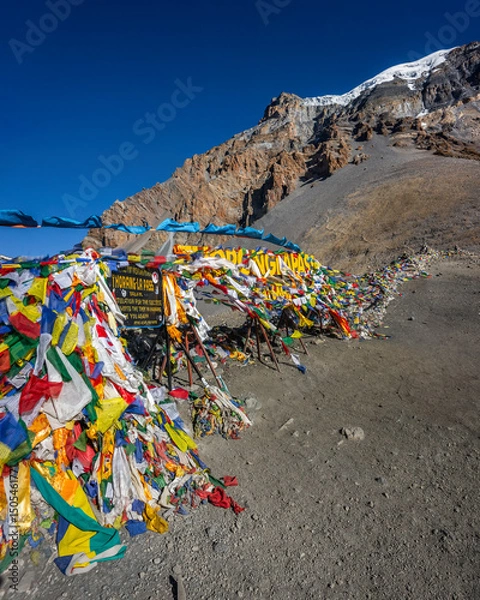 Obraz The waving prayer flags at the top of Thorung La Pass, the highest point of the Annapurna Circuit Trek in Himalaya mountains, Nepal, and Yakwakang peak on the horizon.