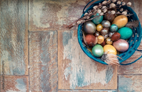 Obraz On the old wooden shabby table a dish with painted in different colors Easter eggs with feathers willow