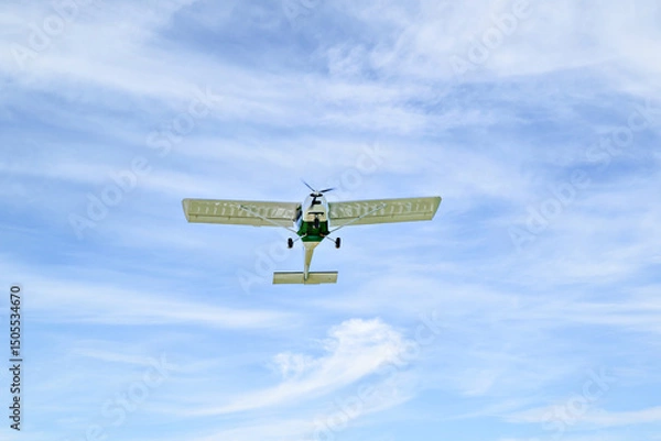 Obraz Single engine ultralight plane flying in the blue sky with white clouds	