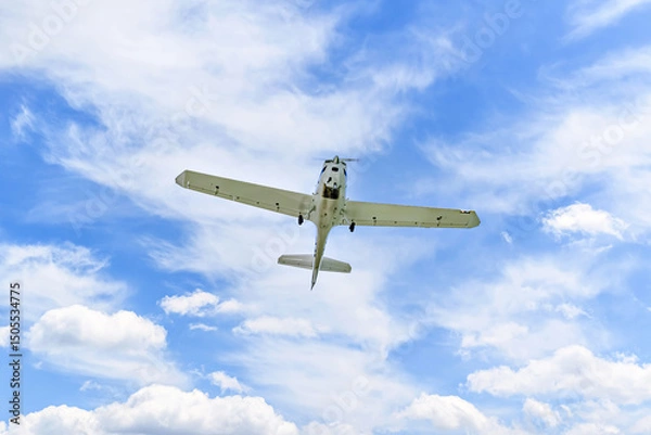 Obraz Single engine ultralight plane flying in the blue sky with white clouds	