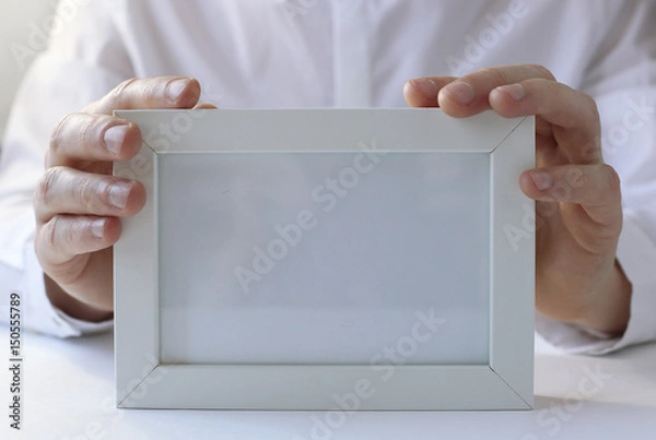 Obraz White photo frame in hands.