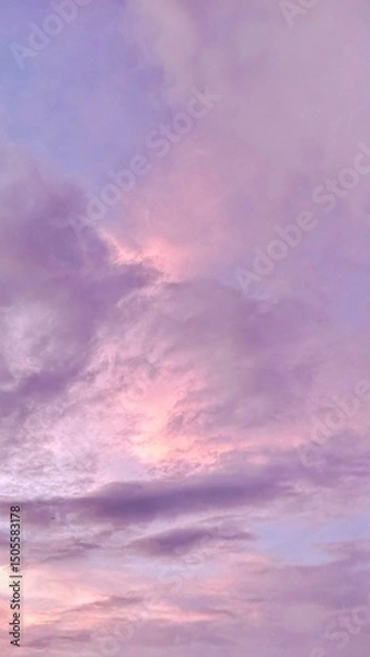 Fototapeta Vertical shot of pastel sky with purple and pink clouds during sunset, soft and dreamy atmosphere perfect for backgrounds, mood boards, or aesthetic visuals.