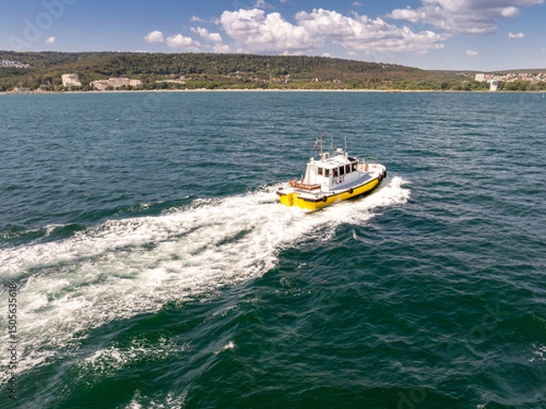 Fototapeta Pilot boat crashing through waves, going to a cargo ship.