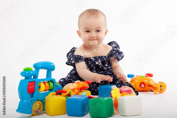 Fototapeta Happy Baby Playing with Colorful Toys on White Background. Early childhood development and joyful playtime.