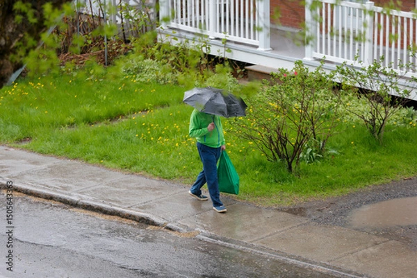 Fototapeta Un homme avec un parapluie marche sous la pluie dans la ville.