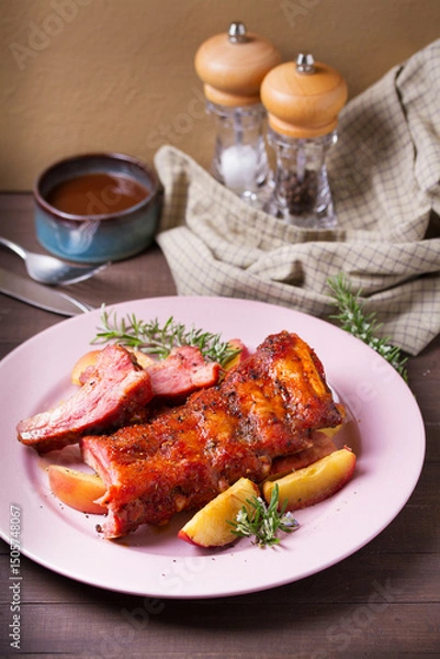 Fototapeta Roasted rack of pork ribs with apples on a plate and brown wood background