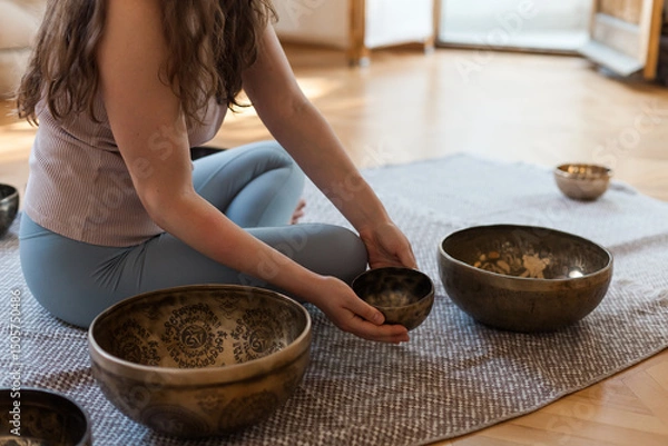 Obraz Sound healing ceremony in a yoga studio with Tibetan singing bowls, incense, and meditating participants. Peaceful atmosphere with natural light and warm tones