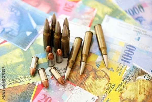 Fototapeta Swiss franc banknotes and bullets. The current francs money bills and ammo lies on table