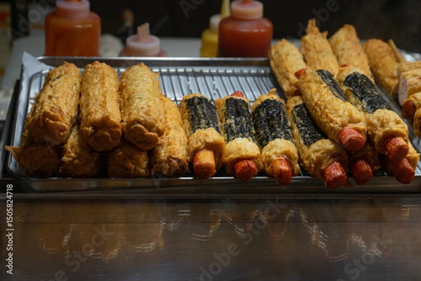 Fototapeta Korean street food with a tempting mood, hot dog tempura and seaweed rolls on display at Myeongdong Market, Seoul, South Korea