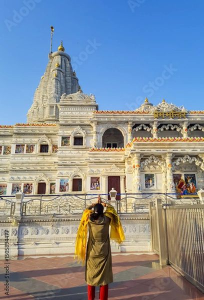 Fototapeta ancient white marble architecture with devotee offering salutation at dusk from flat angle