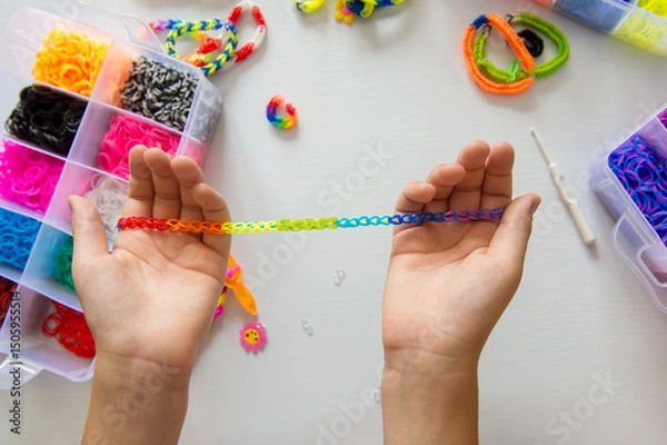 Fototapeta Child's hands crafting colorful rainbow loom bracelet with elastic bands