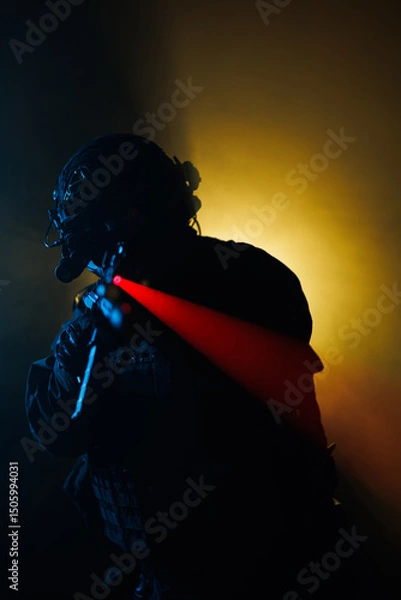 Fototapeta Soldier in tactical gear aiming weapon with illuminated scope against dramatic lighting