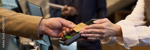 Fototapeta Close-up of hands exchanging credit card at checkout terminal during payment process. Handing over card for transaction at modern point-of-sale device