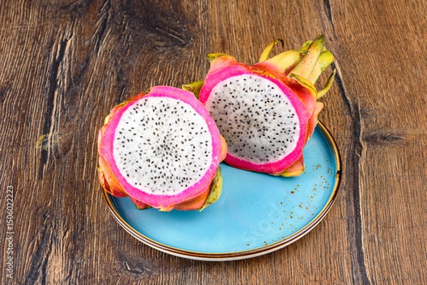 Obraz Halves of fresh and juicy pitahaya on a blue plate.