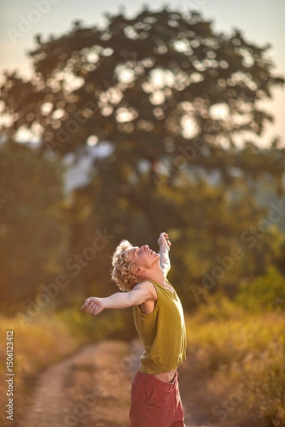 Fototapeta Joyful person enjoying nature on a sunny path surrounded by greenery in the evening light