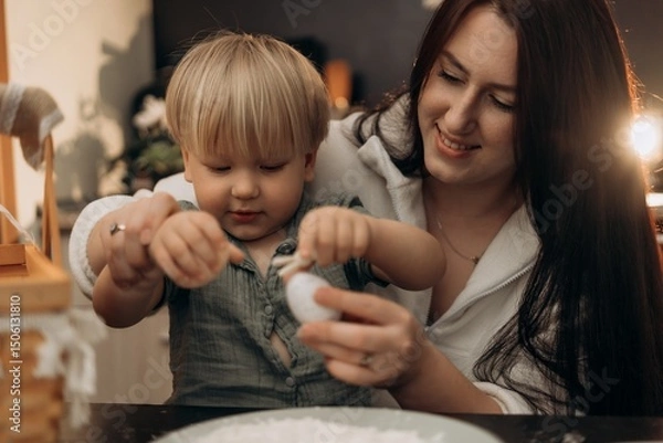Fototapeta Holiday kitchen rituals unfold as a mother guides her toddler in joyful eggs and craft details combining mindful parenting creativity warmth slow childhood and cozy home moments