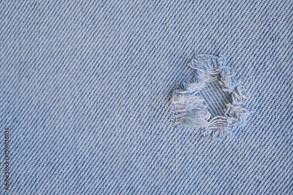 Fototapeta torn light grey denim surface, denim fringe , hole macro texture of blue denim, torn blue denim texture as background photo close up from above	
