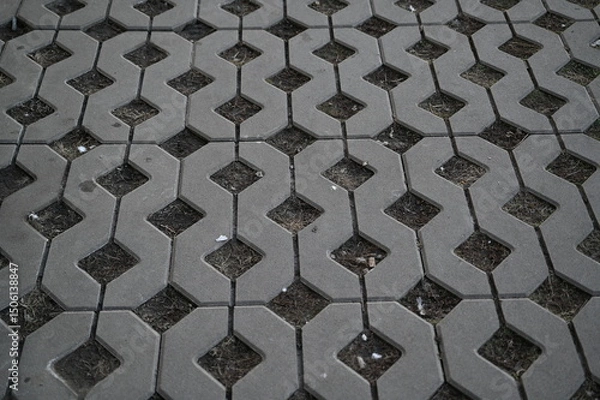 Fototapeta Background texture of square tiles made of gray natural stone. Concrete street covering of road, geometric paving pattern, green lawn and eco parking, green parking, sustainable development city	
