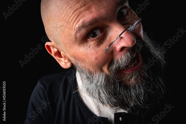 Obraz Funny close-up portrait of a quirky bald man with a long gray beard and eyeglasses, making a silly face. Concept of eccentricity, humor, and expressive personality.