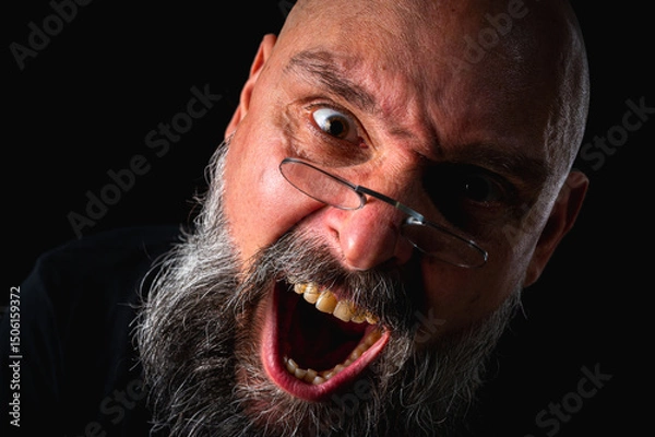 Obraz Funny close-up portrait of a quirky bald man with a long gray beard and eyeglasses, making a silly face. Concept of eccentricity, humor, and expressive personality.